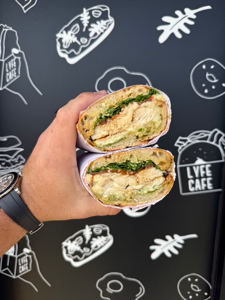Chicken pesto wrap held up against branded wall