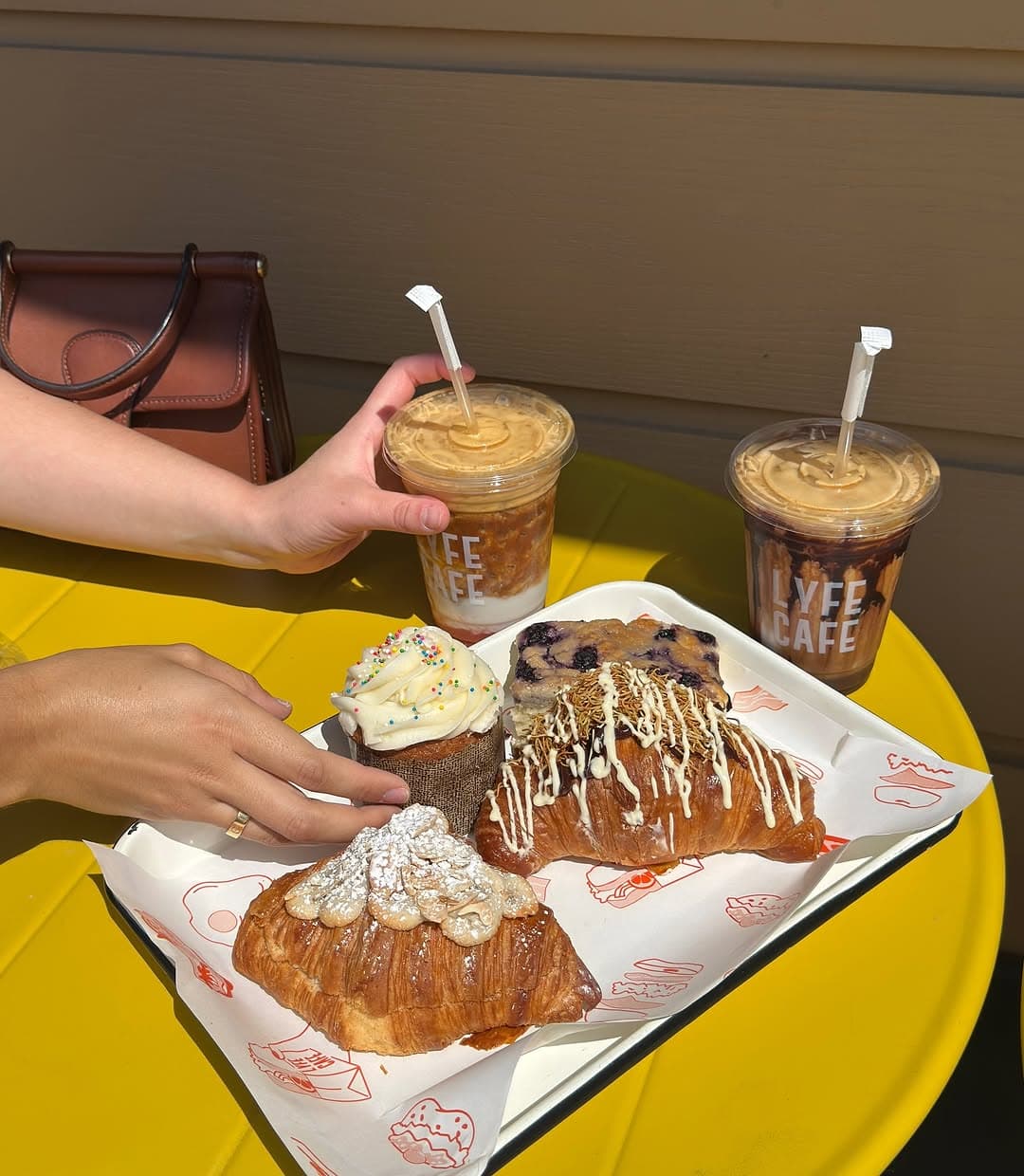 Iced coffees and pastries on yellow table